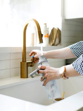 Hands Of Woman Filling Water Bottle In Kitchen Sink