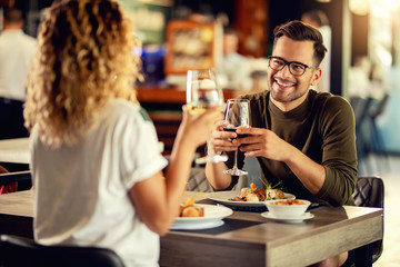 Happy couple drinking wine and talking while eating in a restaurant.