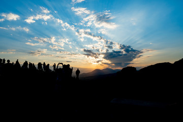 Sticker - Silhouette of fo foreground hills and rocks of Meteora at sunset with crowd of tourists gathered to experience and photograph