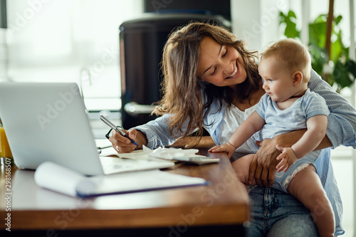 Fotografía Happy mother talking to her baby while working at home.