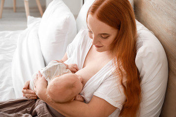 Wall Mural - Young woman breastfeeding her baby at home