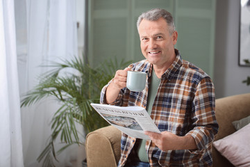 Canvas Print - Portrait of stylish mature man with newspaper and cup of coffee resting at home