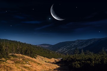 Moon above a mountain top . Beautifully summer landscape . Crescent moon with beautiful sunset background . Generous Ramadan . Light from sky . Religion background .