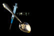 Drugs. Syringe, spoon with heroin and ampoule on a black background.	