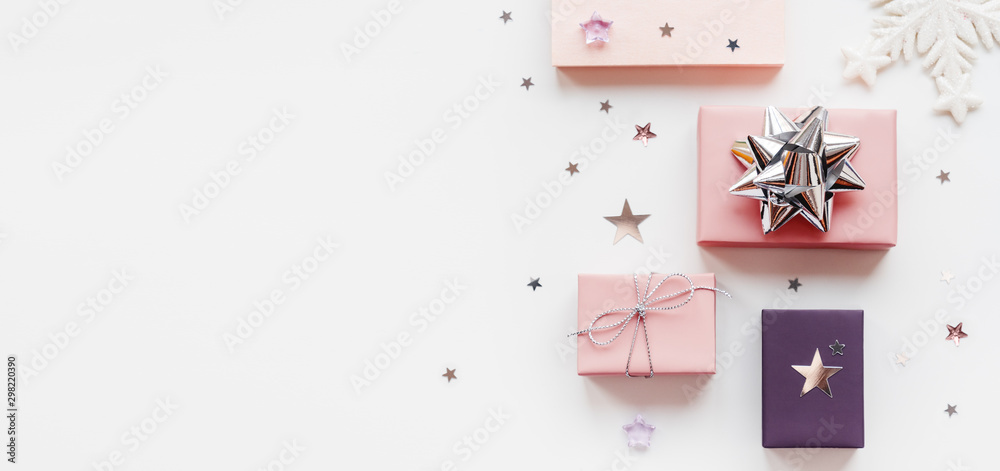 Banner with holiday presents. Gifts wrapped in pale pink and violet paper with silver ribbons and bow. Stars confetti and white copy space. Top view, flat lay. - obrazy, fototapety, plakaty 
