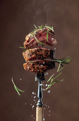 Wall Mural - Grilled ribeye beef steak with rosemary on a brown background.