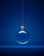 Glass christmas bauble hanging in front of luxury dark blue background.