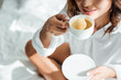 © LIGHTFIELD STUDIOS - cropped view of woman drinking coffee from cup at morning