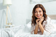 © LIGHTFIELD STUDIOS - smiling woman lying in bed and looking at camera at morning