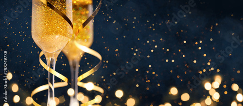 Fotomural Two glasses of champagne with golden confetti, glitter, serpentine and lights