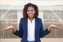 Cheerful Confused Female Manager Posing Outside. Young Black Business Woman Standing Near Outdoor Glass Wall, Looking At Camera, Shrugging. Doubt Or Question Concept