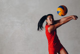 Young Asian woman volleyball player in red uniform takes ball