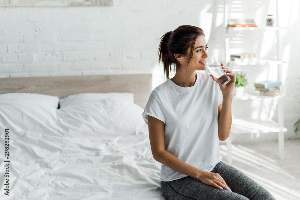 beautiful happy girl holding drinking water from glass in the morning - obrazy, fototapety, plakaty 