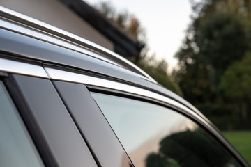 Wall Mural - Detailed, shallow focus view of a Swedish-built SUV cars side door window and part of the metallic roof rack. Shown at a private residence.