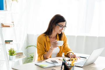 Poster - beautiful freelancer working on laptop with coffee cup in home office