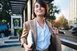 © Anton - Young pretty smiling stylish businesswoman with laptop joyfully looking in camera on city street