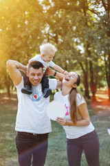 Happy parents play in the park with their child.