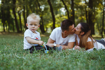 Wall Mural - Happy family in a park on the green grass.