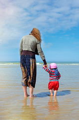 Wall Mural - beautiful little girl playing on the beach with her mom