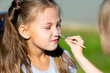 © ALEXEY - Children apply aqua makeup on their faces. Brother and sister paint each other s faces on the street in park