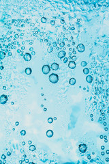 Wall Mural - transparent background of soda water and ice with bright blue bubbles within the glass