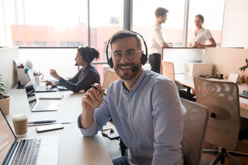 Millennial happy male call center agent looking into camera.