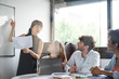 © PhotoAlto - Young businesswoman giving presentation to her colleagues in office