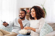 People And Leisure Concept - African American Couple With Popcorn Watching Tv At Home