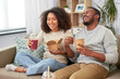 © Syda Productions - eating and people concept - happy african american couple with takeaway food and drinks at home