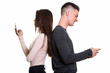 © Ranta Images - Profile view of angry young couple using mobile phone with backs