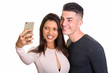 © Ranta Images - Happy young couple smiling while woman taking selfie together wi