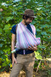 © Viktor Kochetkov - Young hipster father holding, wearing, carrying sling scarf with baby inside. Nature, outdoors, sunny day.