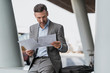 © Daniel Ingold/Westend61 - Businessman reviewing papers outdoors