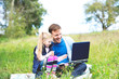 © Roman Maerzinger/Westend61 - Father and daughter sitting on meadow, father working on laptop