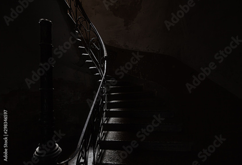 Fotografía An ancient screw staircase in a dark entrance, a small ray of light illuminates the steps