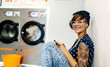 © Marco Govel/Westend61 - Portrait of tattooed young woman hearing music with earphones in a launderette