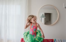 Young Girl With Inflatable Ring And Swimming Costume Stood At Home