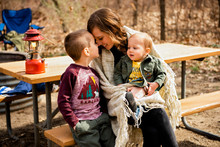 Smiling Mother Cuddles Sons Camping In Fall Picnic Area