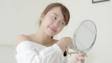 Wall Mural - Beautiful young asian woman applying powder with brush looking mirror, beauty girl makeup face with blush cosmetic, facial with skin care and health concept.