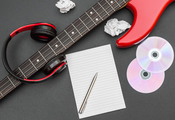 Wall Mural - Blank notepad with electric guitar and headphones on black. Creating music.