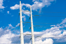 A Low Angle View Of Twin Electric Poles Supporting Medium Voltage Wires With Insulators And Access Ladders For Maintenance, Urban Utilities Infrastructure.