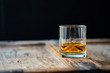 © stock mp - Beautiful whiskey glass on a shabby used wooden table in front of dark background