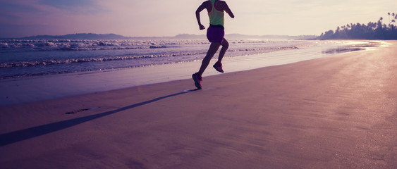 Young fitness woman running at sunrise beach