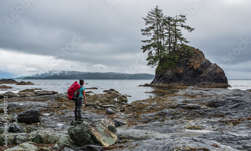 Backpacking woman lookout out onto ocean on the west coast trail, Vancouver Island, British Columbia, Canada