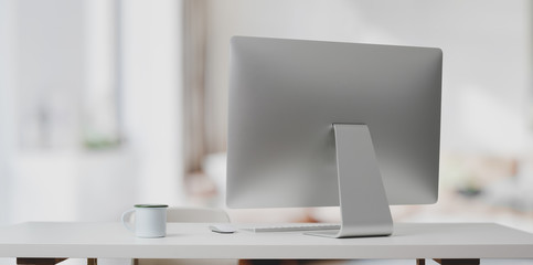 Desktop computer on white table and coffee cup in modern office with blurred background