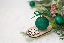 Christmas Winter Wooden Sleigh With Green Bauble Over The Snow. Abstract Winter Greeting Card With Copy Space.