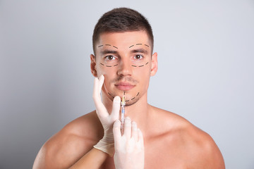 Wall Mural - Man getting facial injection on grey background. Cosmetic surgery