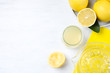 Flat lay composition with freshly squeezed lemon juice on white wooden table. Space for text