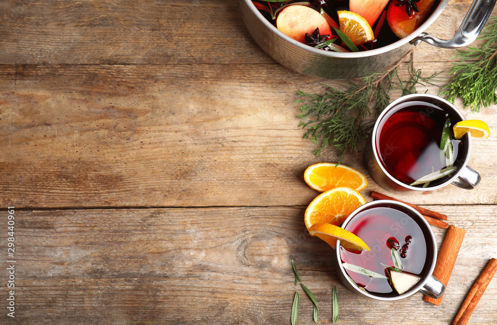 Tasty mulled wine with spices on wooden table, flat lay. Space for text - obrazy, fototapety, plakaty 