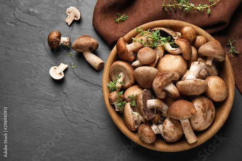 Fotografía Different fresh wild mushrooms in bowl on black background, flat lay
